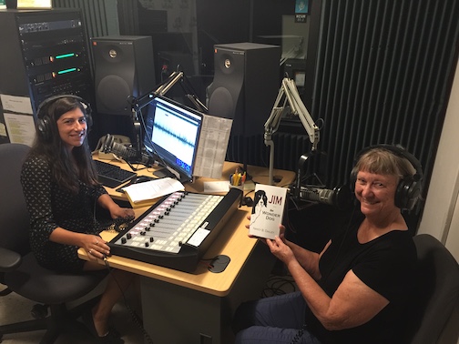 In the recording studio, Producer Suzanne Hogan interviews author Nancy Dailey about Jim the Wonder Dog of Marshall, Missouri. Nancy is holding a copy of her book, JIM aka The Wonder Dog.